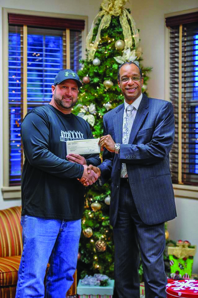 DEC Lineman Shane Payne accepts a check from WBOC’s Bless Our Children program from anchor Paul Butler.