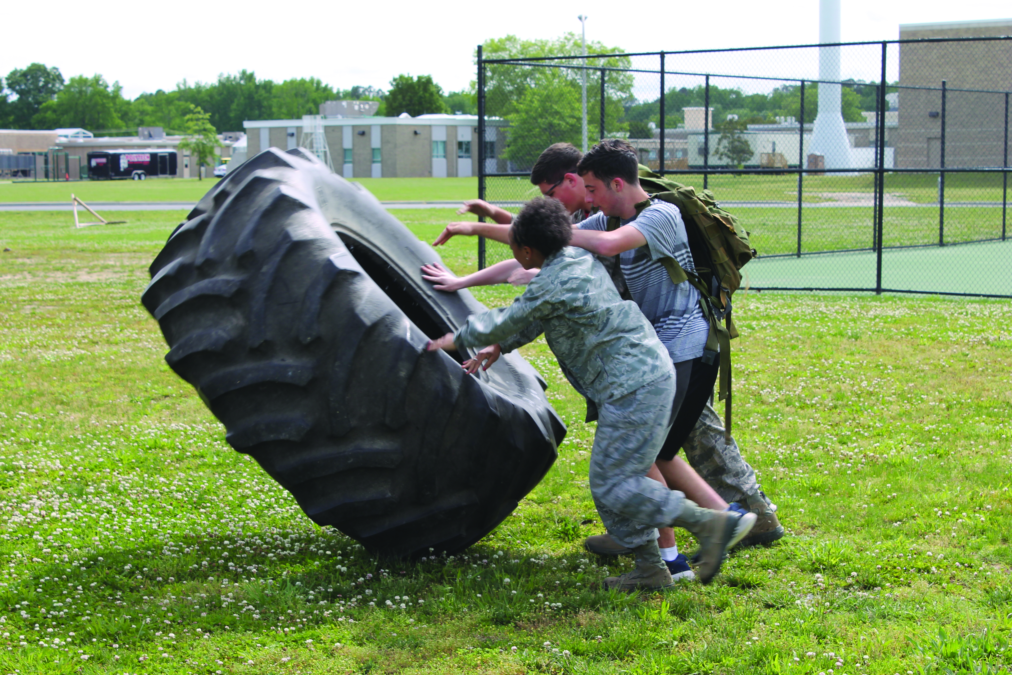 Three cadets practice flipping a tire.