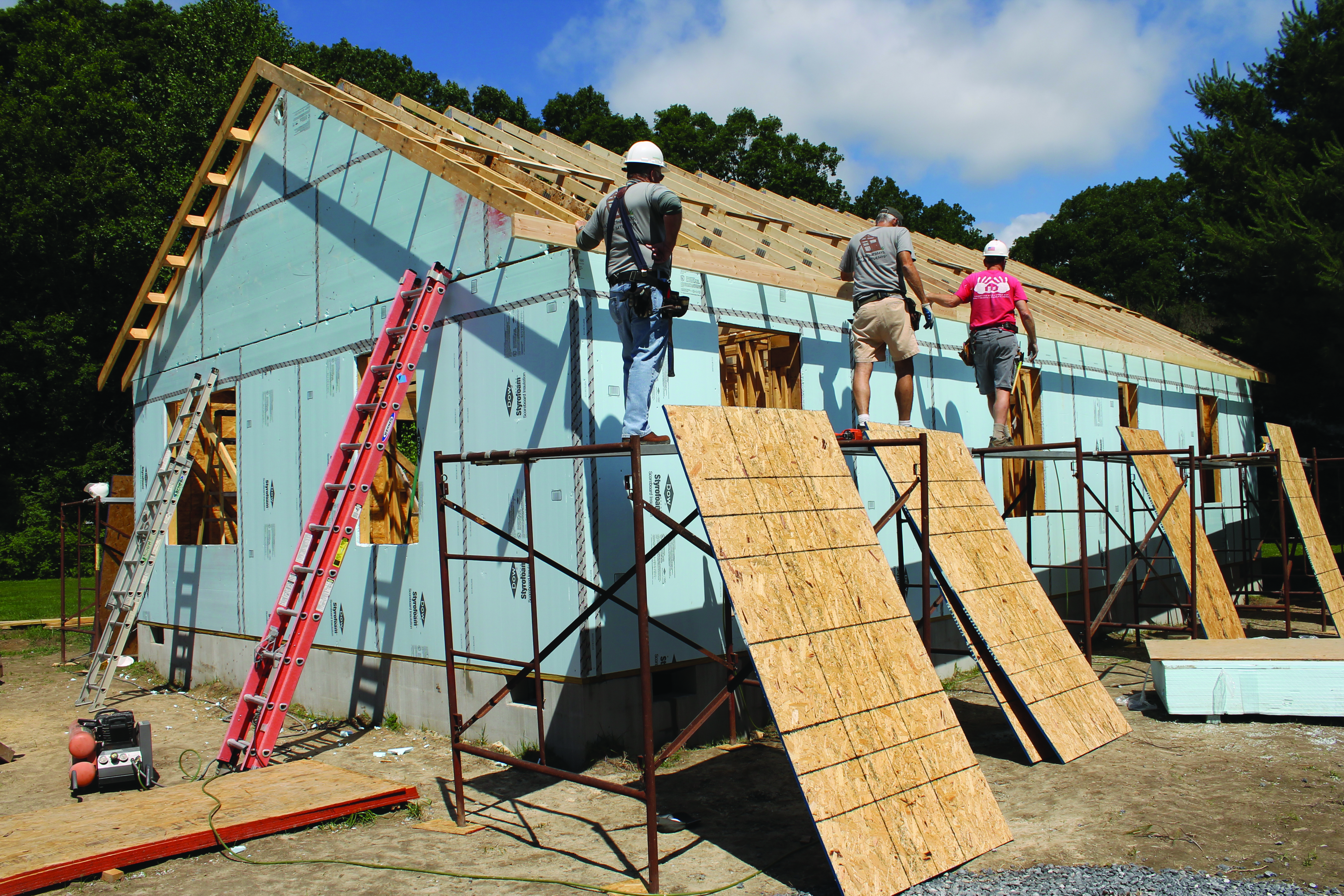 Volunteers work to set rafters on a Habitat home in Milton.
