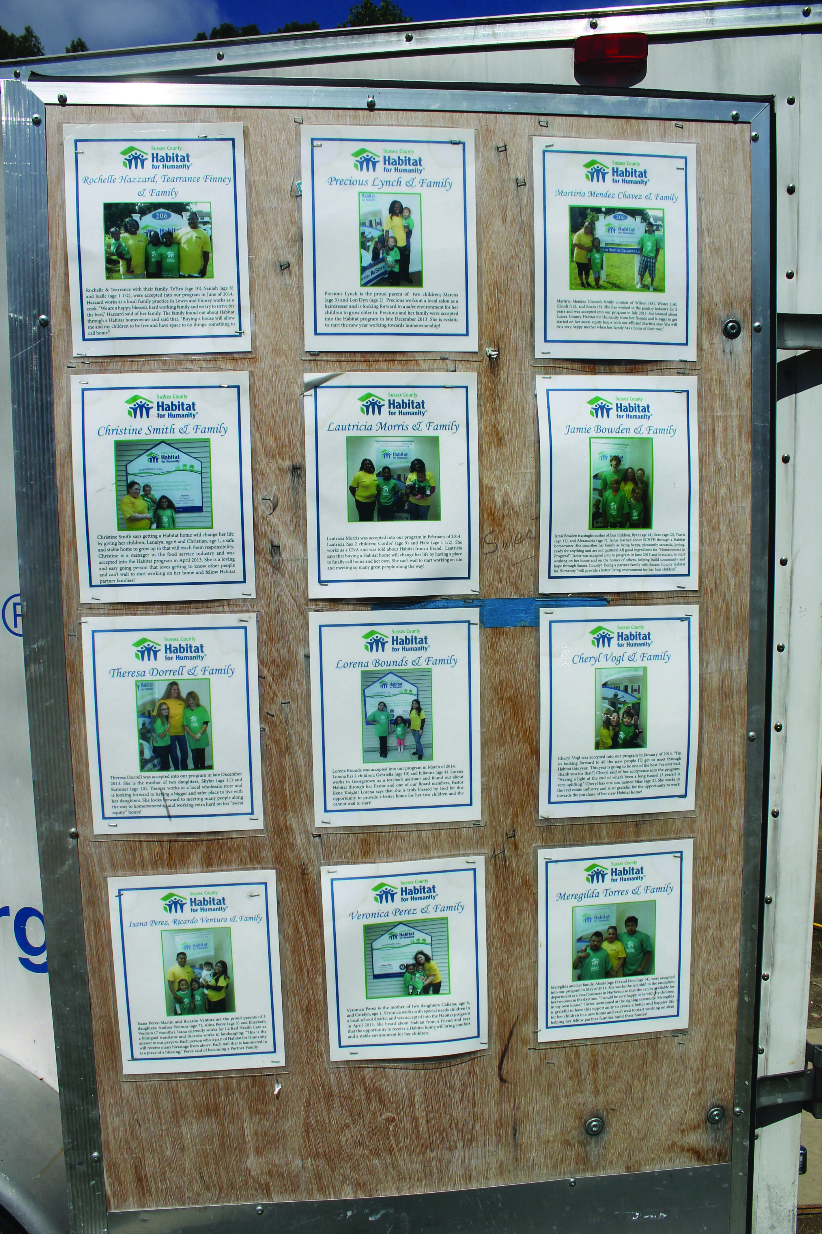 A door panel on one of Habitat for Humanity’s work trailers, showing the pictures of families helped by the organization.