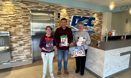 DEC employees stand with some of the gifts they and their coworkers donated in support of Children's Choice, and their mission to provide presents to children in need.