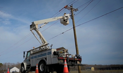 A lineworker works to restore power along Delaware roadways, using safety cones and their truck's strobe lights to alert drivers to their presence.
