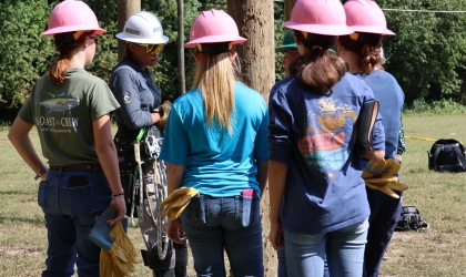 DEC’s Megan Simmons, apprentice line worker instructs Girl Power Camp attendees on safety protocol for climbing poles, and assists as they practice.