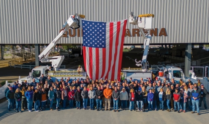 DEC employees stand in front of two line trucks.