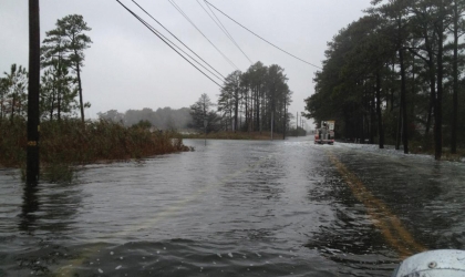 A DEC truck faces a roadway flooded by water following a major storm.