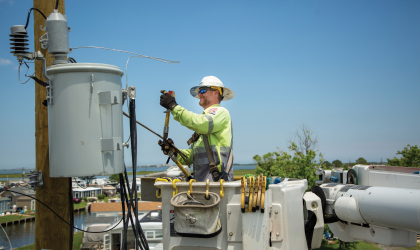A DEC lineworker restores power using a bucket truck to reach a pole-top transformer.