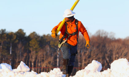 A DEC lineworker maneuvers through deep snow to begin his work of restoring service to members the morning after the February 22 blizzard.