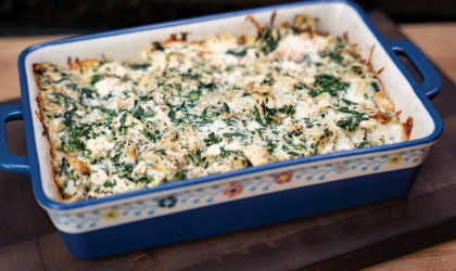 Photo of DEC's featured recipe: Cheesy Spinach Chicken Bake — prepared in a colorful, floral-themed casserole dish.