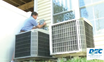 An HVAC technician assesses and adjusts outdoor home-cooling units.
