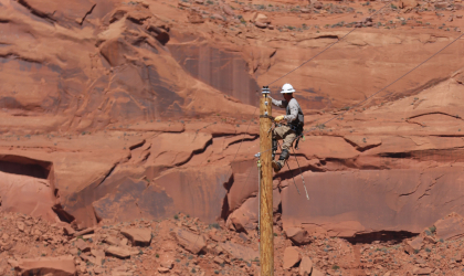 A DEC lineworker works atop a utility pole as part of the Light Up Navajo (LUN) initiative — a mutual aid program created to help bring power to more than 9,000 Navajo families.