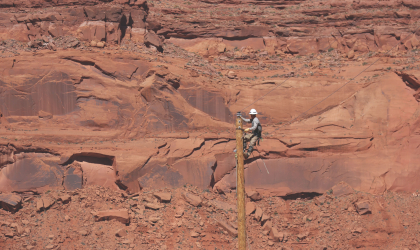 DEC lineworker Zane Lawson works atop a utility pole to install powerlines