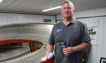 DEC’s Kevin Colborn’s life has been anything but ordinary. Here, he poses for a photo in front of his home slot car track.