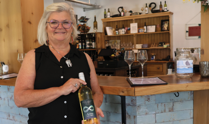 Shauna Thompson — owner of Twin Branch Winery outside of Milton — poses for a photo holding one of Twin Branch's signature blends in the winery's tasting room.
