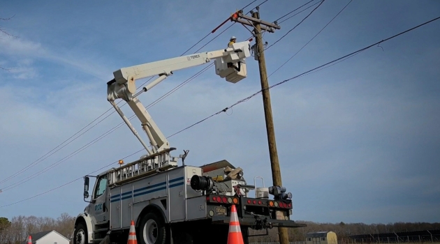 A lineworker works to restore power along Delaware roadways, using safety cones and their truck's strobe lights to alert drivers to their presence.