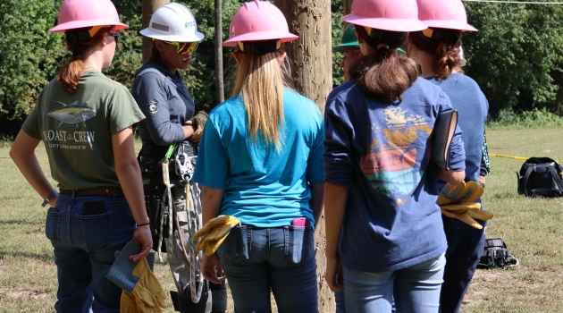 DEC’s Megan Simmons, apprentice line worker instructs Girl Power Camp attendees on safety protocol for climbing poles, and assists as they practice.