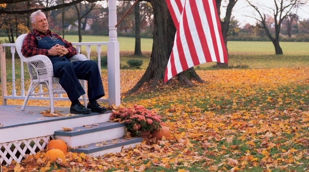 A man sits on his porch, enjoying a fall day.