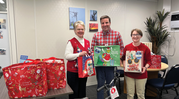 DEC employees stand in front of gifts brought in for this year's Children's Choice Angel Tree initiative.