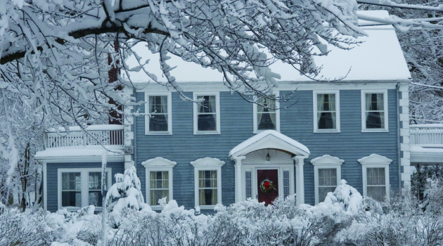Snow covers the roof of a gray, two-story home, signaling the arrival of winter.