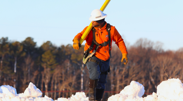 A DEC lineworker maneuvers through deep snow to begin his work of restoring service to members the morning after the February 22 blizzard.