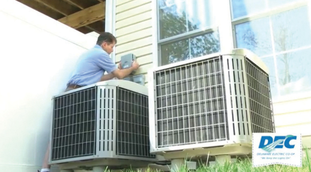 An HVAC technician assesses and adjusts outdoor home-cooling units.