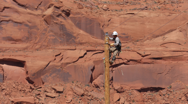 A DEC lineworker works atop a utility pole as part of the Light Up Navajo (LUN) initiative — a mutual aid program created to help bring power to more than 9,000 Navajo families.