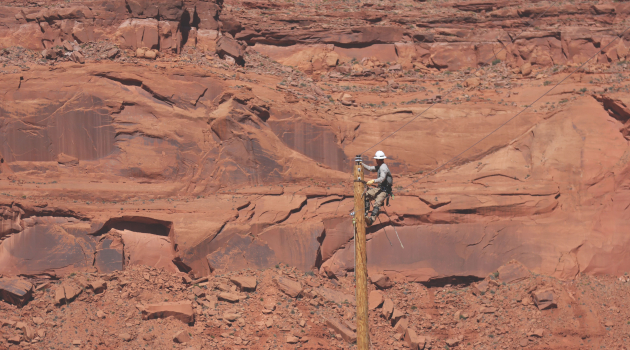 DEC lineworker Zane Lawson works atop a utility pole to install powerlines