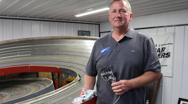 DEC’s Kevin Colborn’s life has been anything but ordinary. Here, he poses for a photo in front of his home slot car track.
