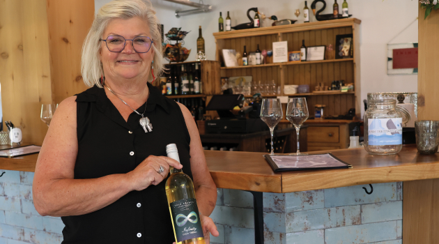 Shauna Thompson — owner of Twin Branch Winery outside of Milton — poses for a photo holding one of Twin Branch's signature blends in the winery's tasting room.